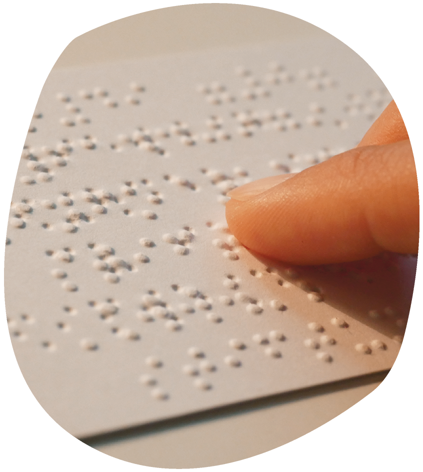 Ein Zeigefinger tastet die Oberfläche einer Braille-Schrift auf einem Papier ab
